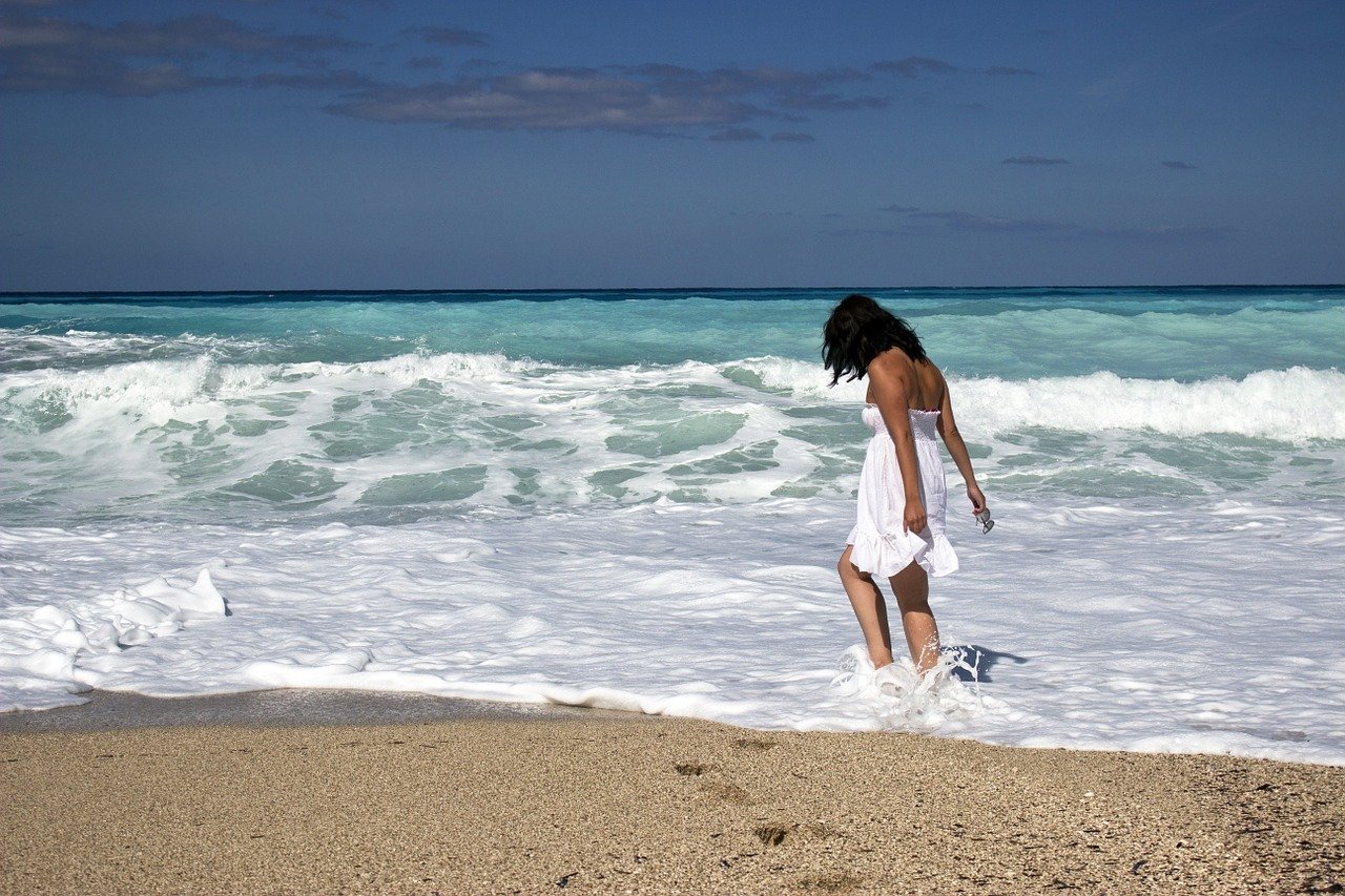 A Person In A White Dress On A Beach Description Automatically Generated With Low Confidence